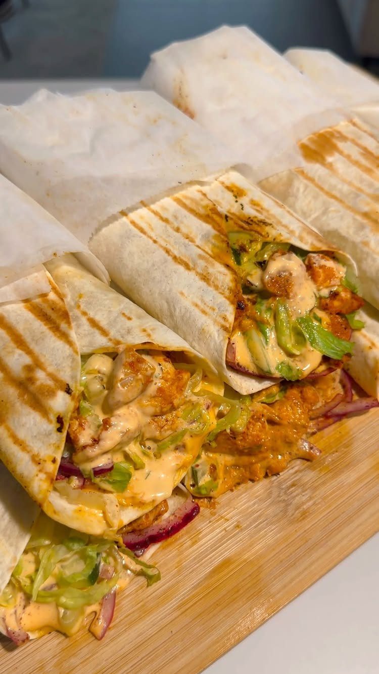 Grilled chicken wraps with lettuce and creamy sauce on a wooden board