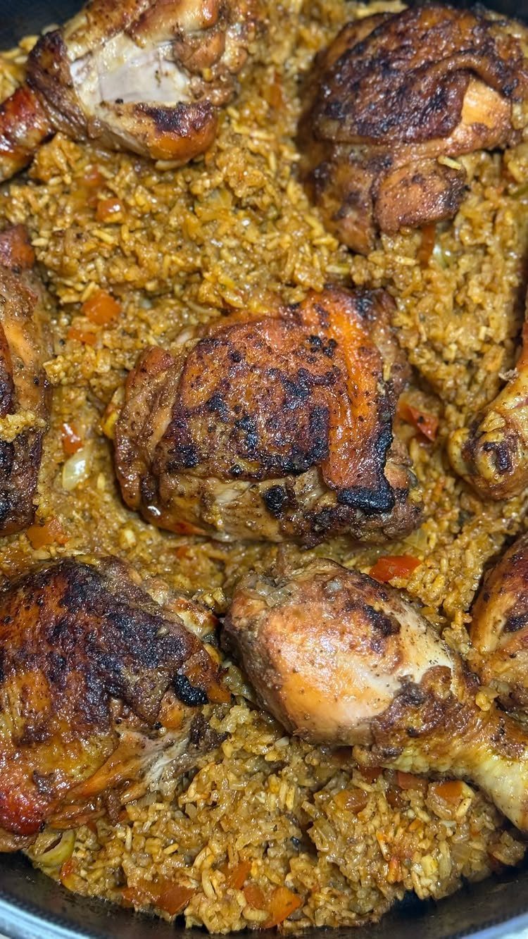 Browned chicken pieces cooked with seasoned yellow rice in a large pot.