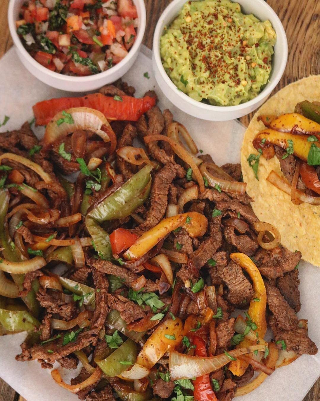 Beef fajitas with sautéed peppers and onions served with guacamole and salsa.
