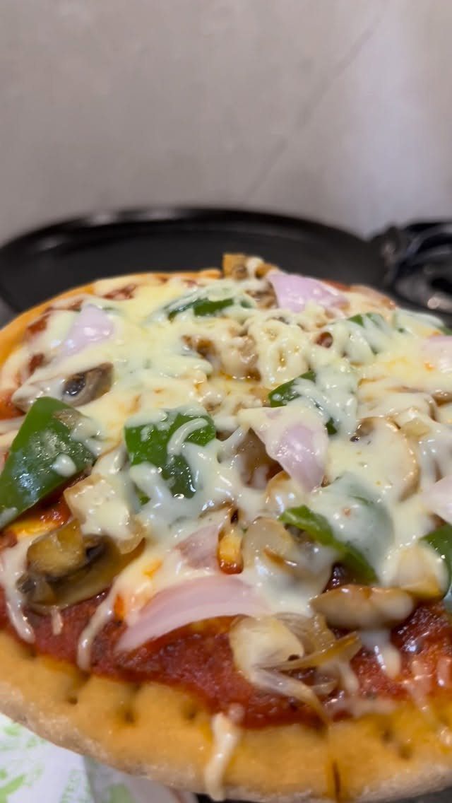 Homemade pizza topped with melted cheese, green peppers, mushrooms, and red onions.