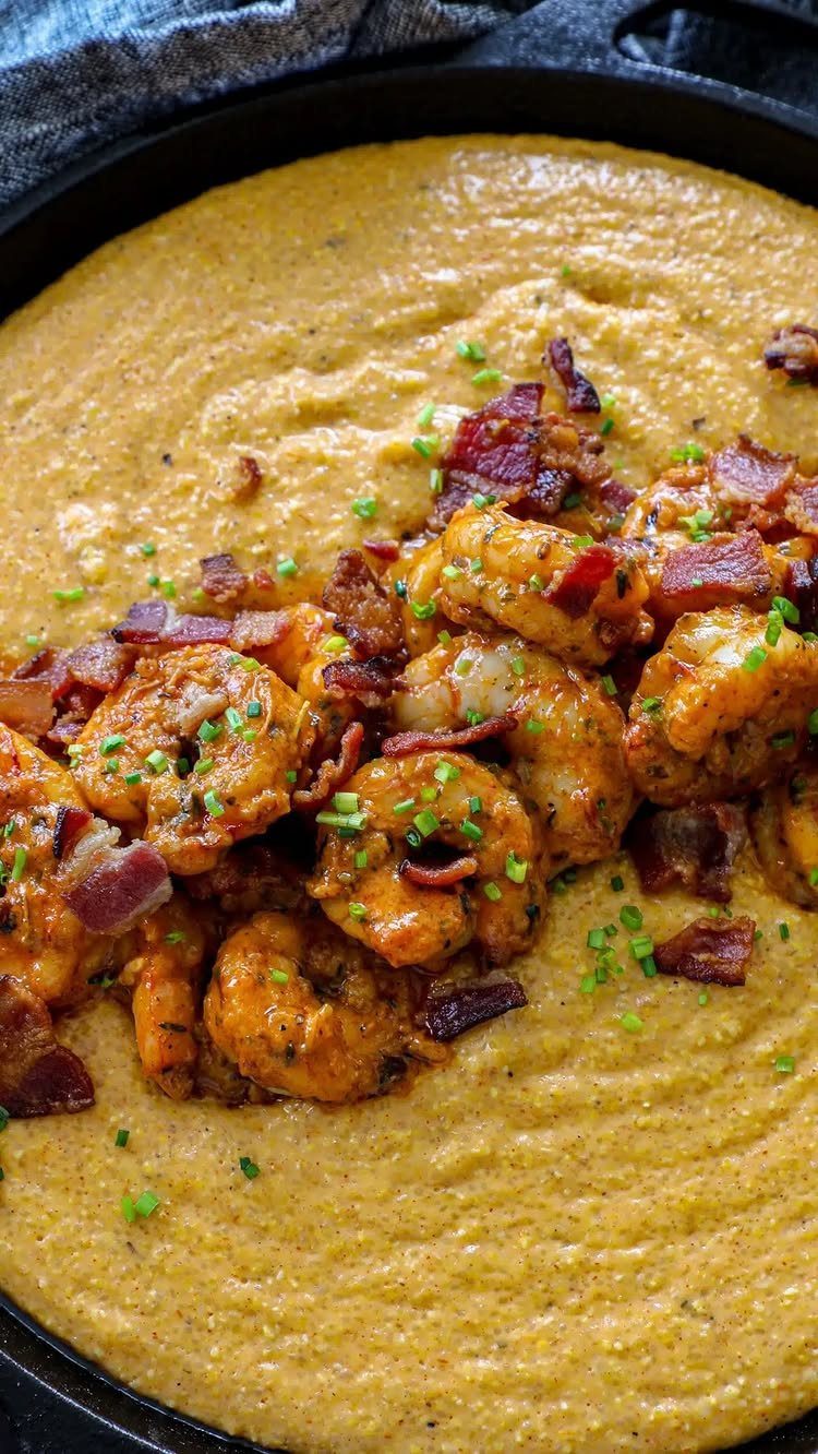 Seasoned shrimp and bacon on creamy yellow grits in a black skillet