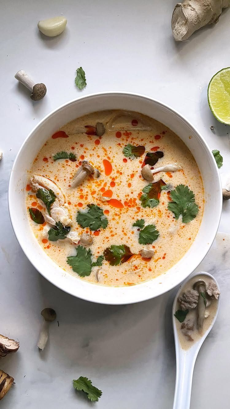 Creamy Thai chicken coconut soup with mushrooms and cilantro in a white bowl.