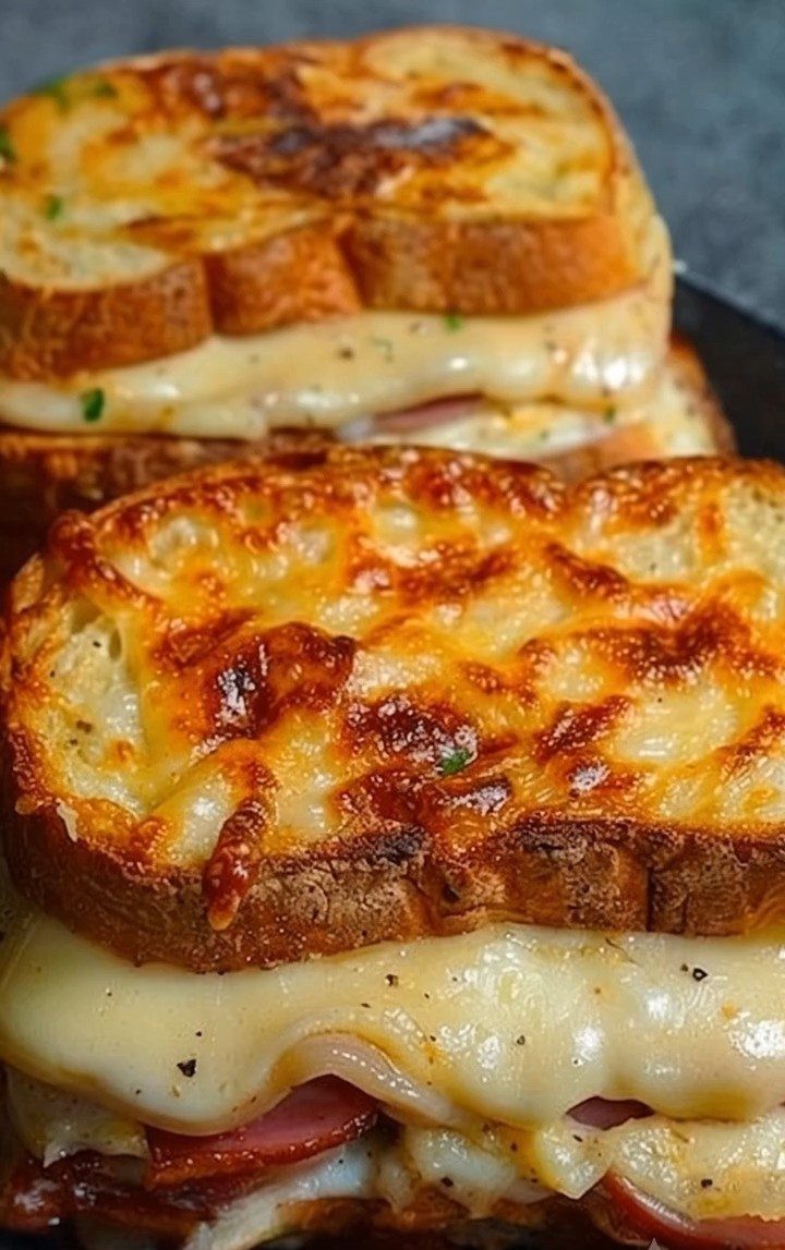 Two toasted bacon grilled cheese sandwiches with melted cheese on thick bread.