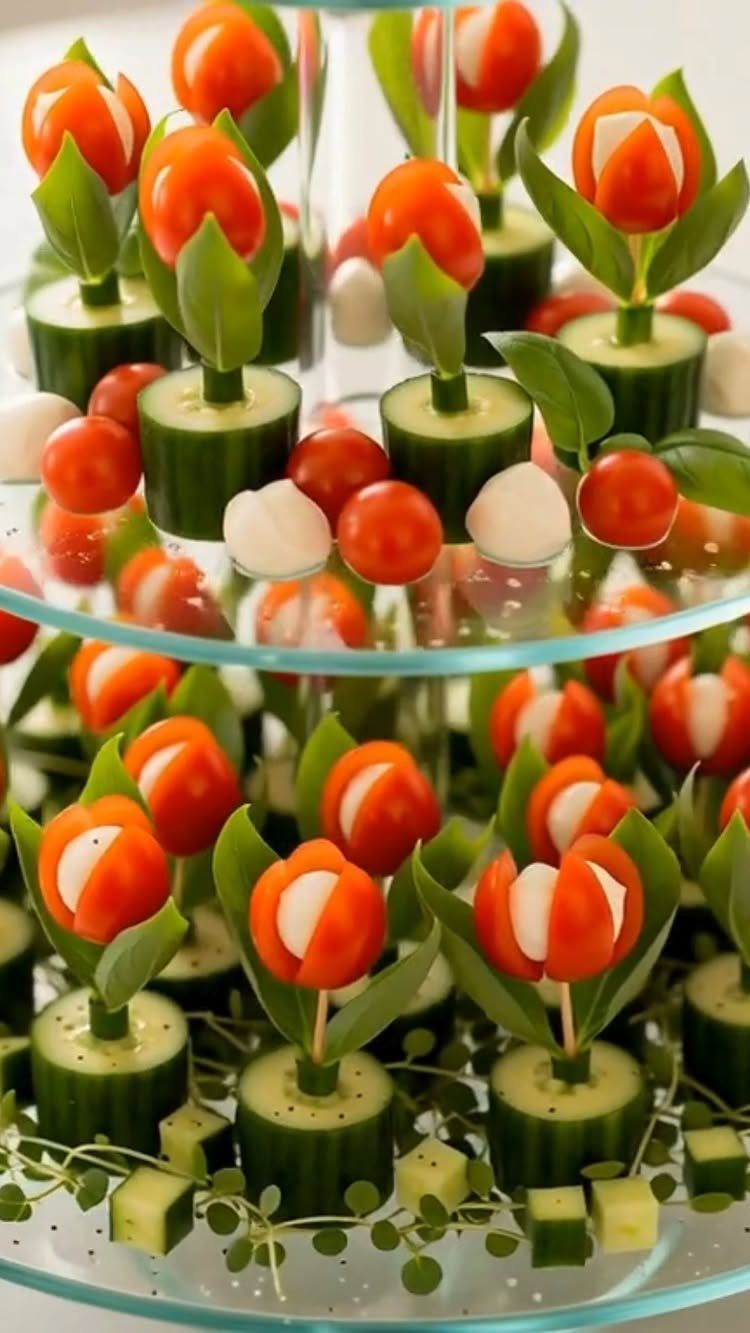 Cucumber and tomato appetizers shaped like tulips on a glass tiered serving stand