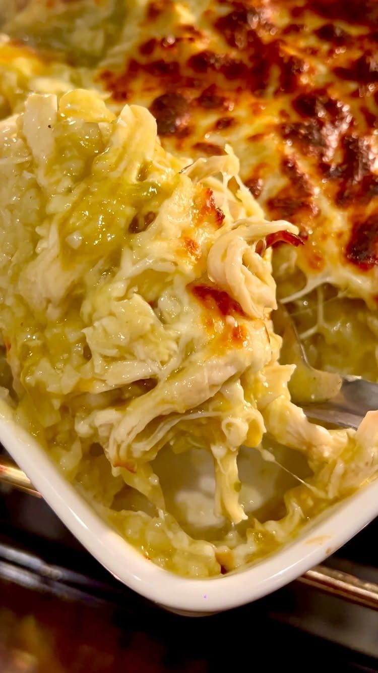 Cheesy chicken enchilada dip with melted cheese and shredded chicken in white dish