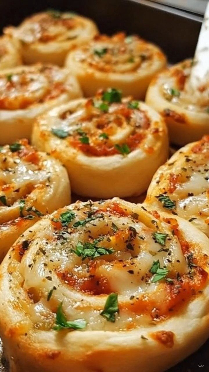 Golden-brown pizza rolls with melted cheese and parsley in a baking pan.