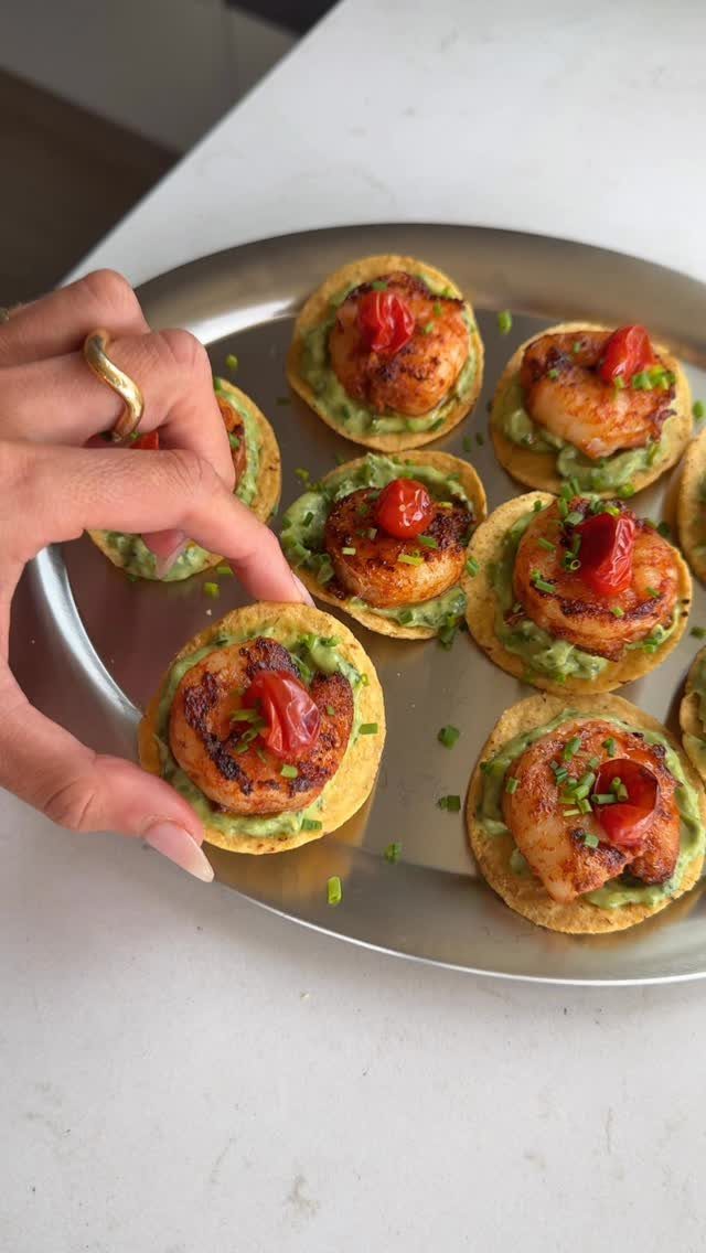 Shrimp and guacamole appetizers on tortilla chips served on a silver platter.