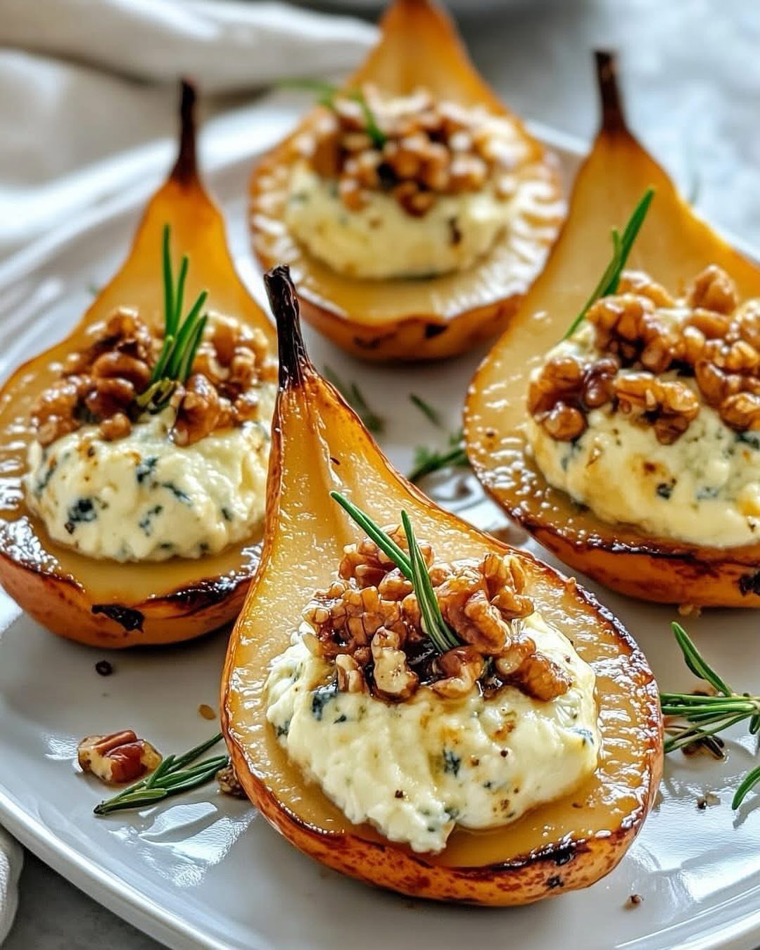 Roasted pear halves filled with creamy cheese, topped with walnuts and rosemary.