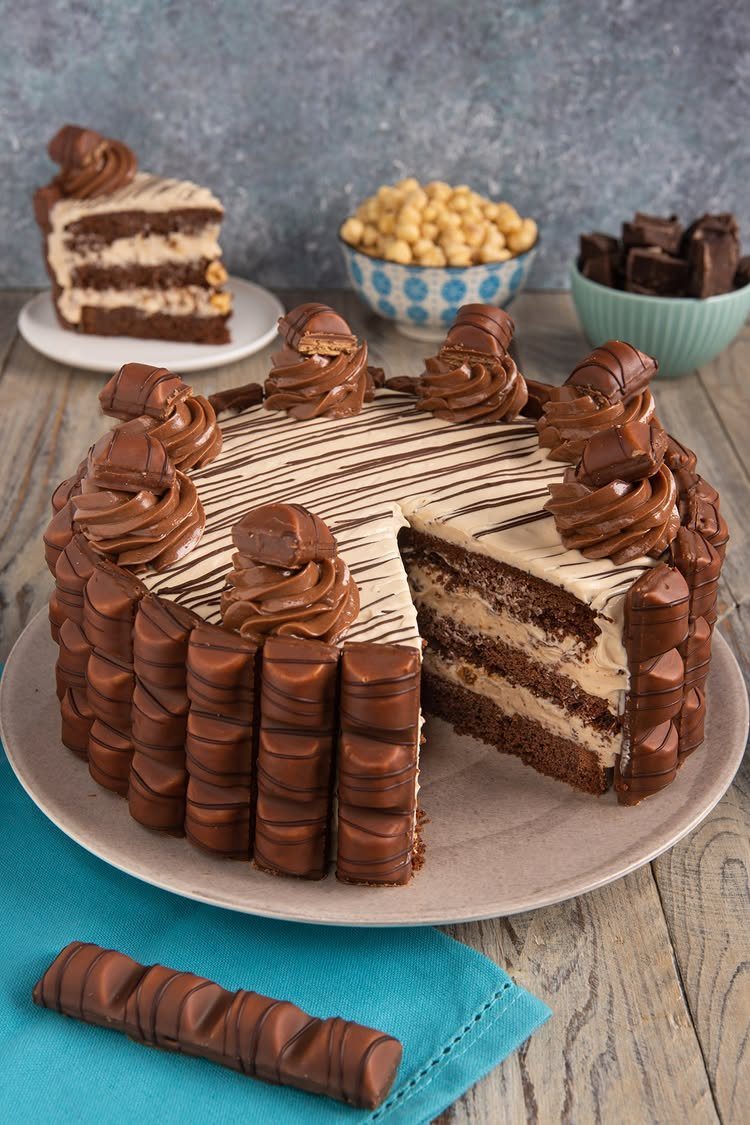 Layered chocolate hazelnut cake decorated with chocolate wafer rolls and frosting swirls.