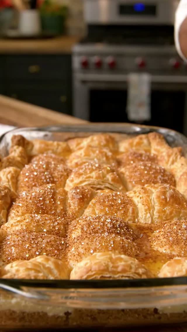 Golden-brown sopapilla cheesecake bars dusted with cinnamon sugar in a glass dish.