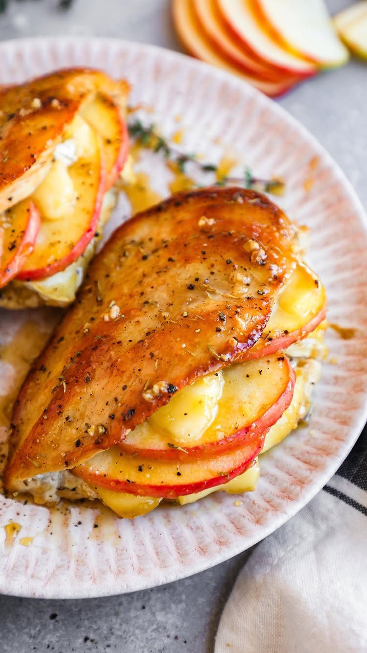 Seared chicken breasts stuffed with sliced red apples on a white textured plate