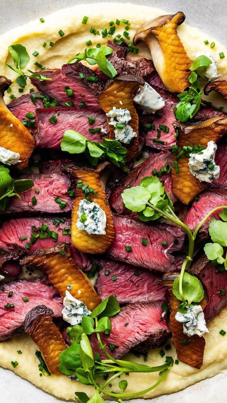 Slices of medium-rare steak and mushrooms with blue cheese on creamy puree.