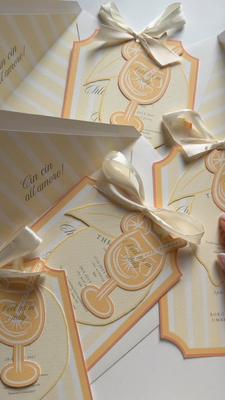 Cream and yellow striped invitation cards with orange borders and white ribbon bows.
