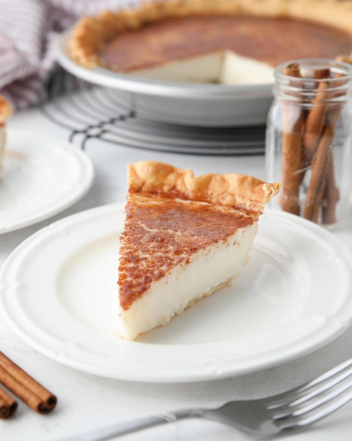 Slice of creamy custard pie with browned top on a white ceramic plate.