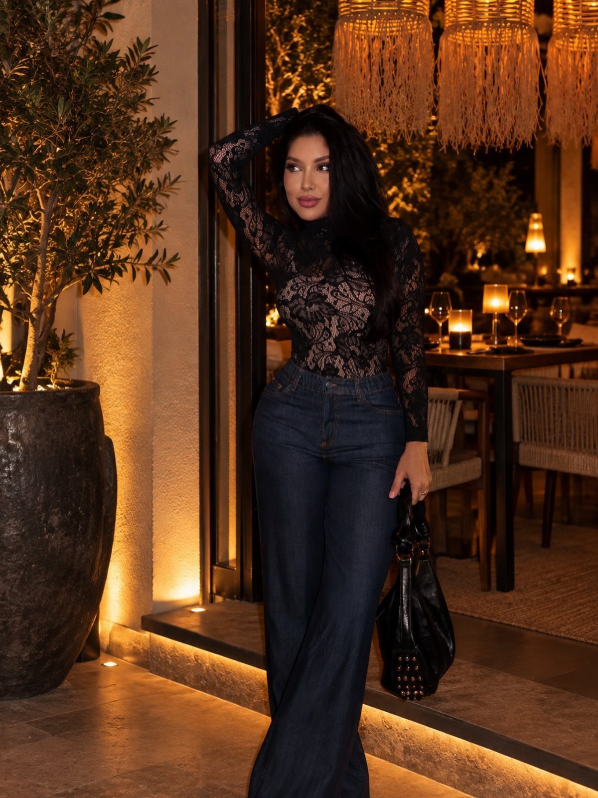 Woman wearing a black lace top and dark wide-leg jeans at night.