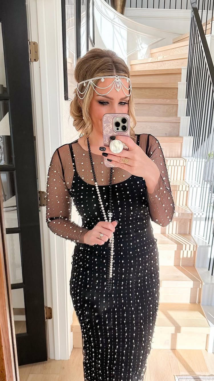 Woman in a black sequined flapper dress and beaded headband taking a selfie.