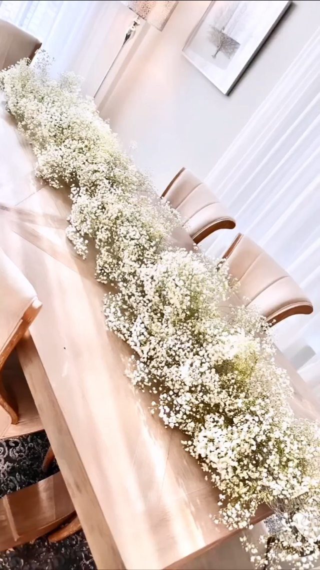 White baby's breath flower runner as a centerpiece on a wooden dining table