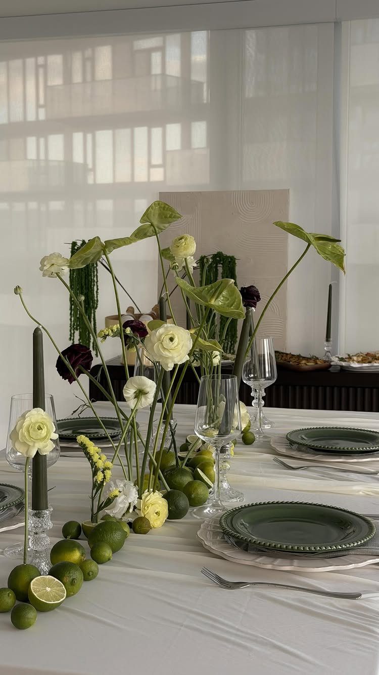 Floral and lime centerpiece on a white dining table with green plates.