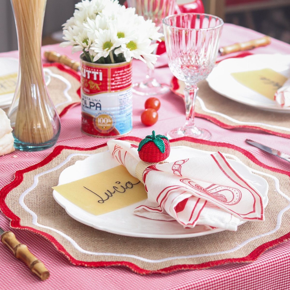 White plate with a tomato napkin ring and a name card for Lucia.