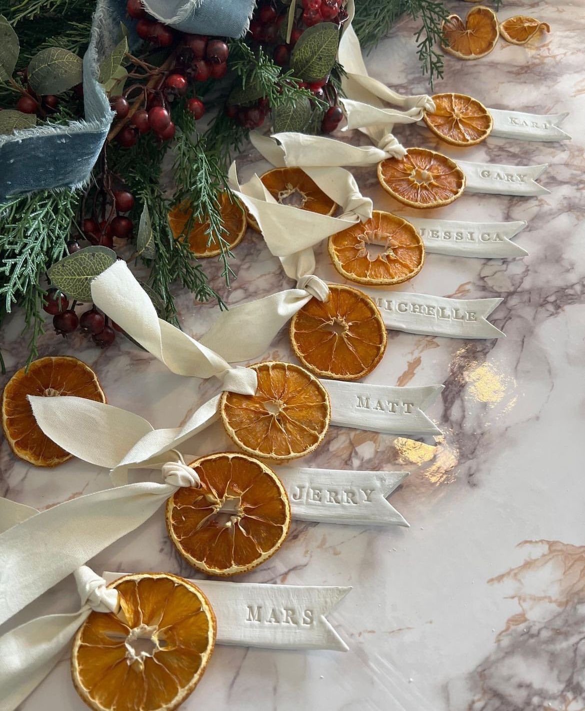 Dried orange slice napkin ties with white ribbons and personalized name tags.
