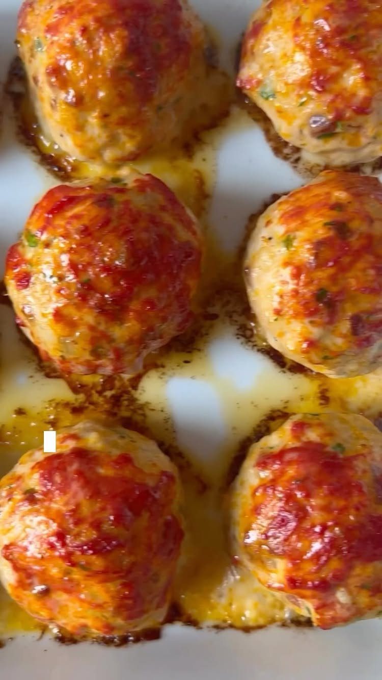 Glazed chicken meatballs with herbs arranged in a white baking dish.