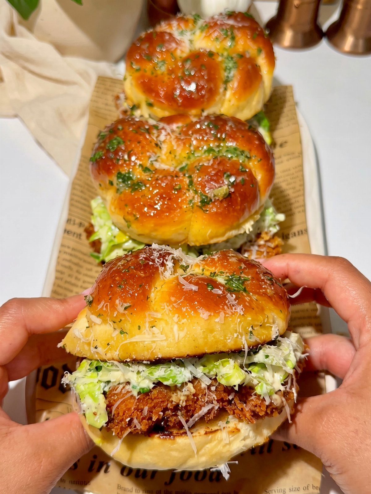 Fried chicken burgers with glossy herb buns and green slaw on parchment paper.