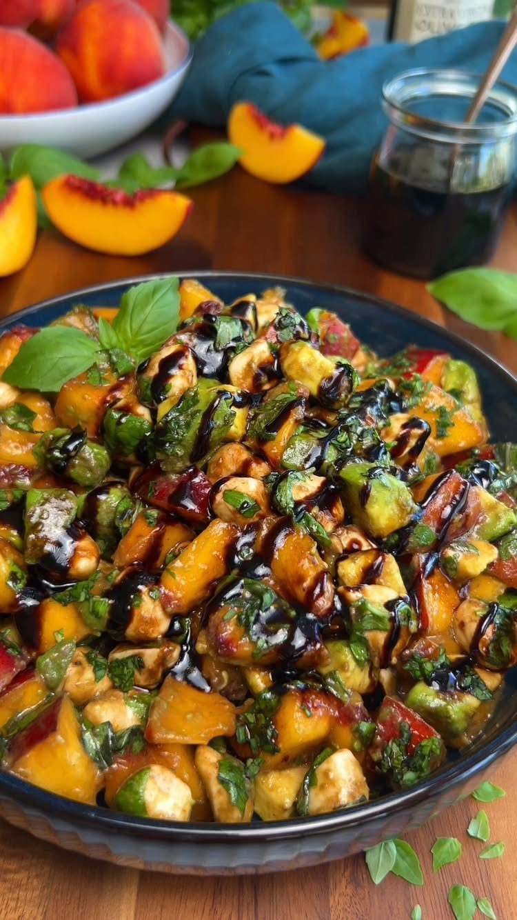Peach, cucumber, and mozzarella salad with balsamic glaze in a blue bowl.