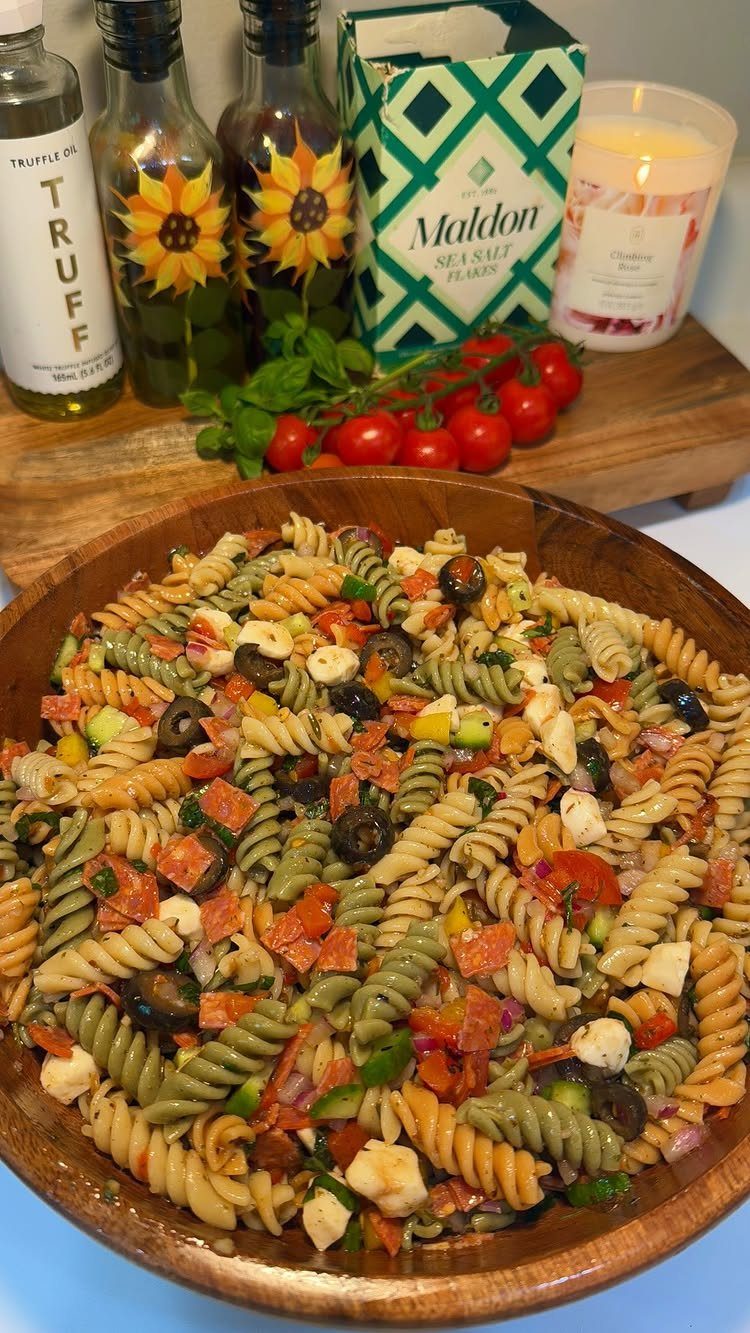 Tri-color rotini pasta salad with olives and feta in a wooden bowl.
