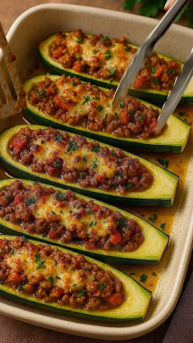 Stuffed zucchini boats with meat and melted cheese in a baking dish.