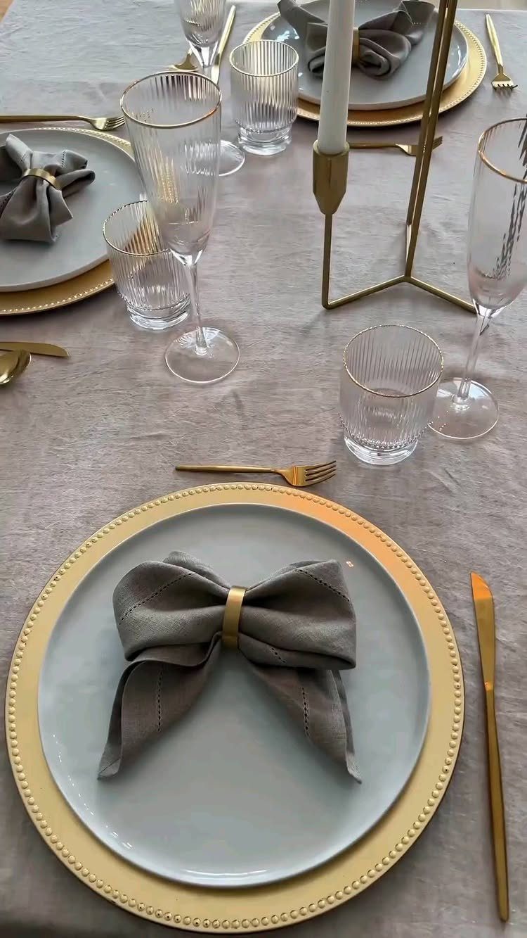 Grey plates and napkins with gold accents on a grey tablecloth setting.