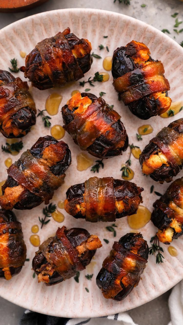 Bacon-wrapped dates stuffed with cheese and drizzled with honey on a ceramic plate.