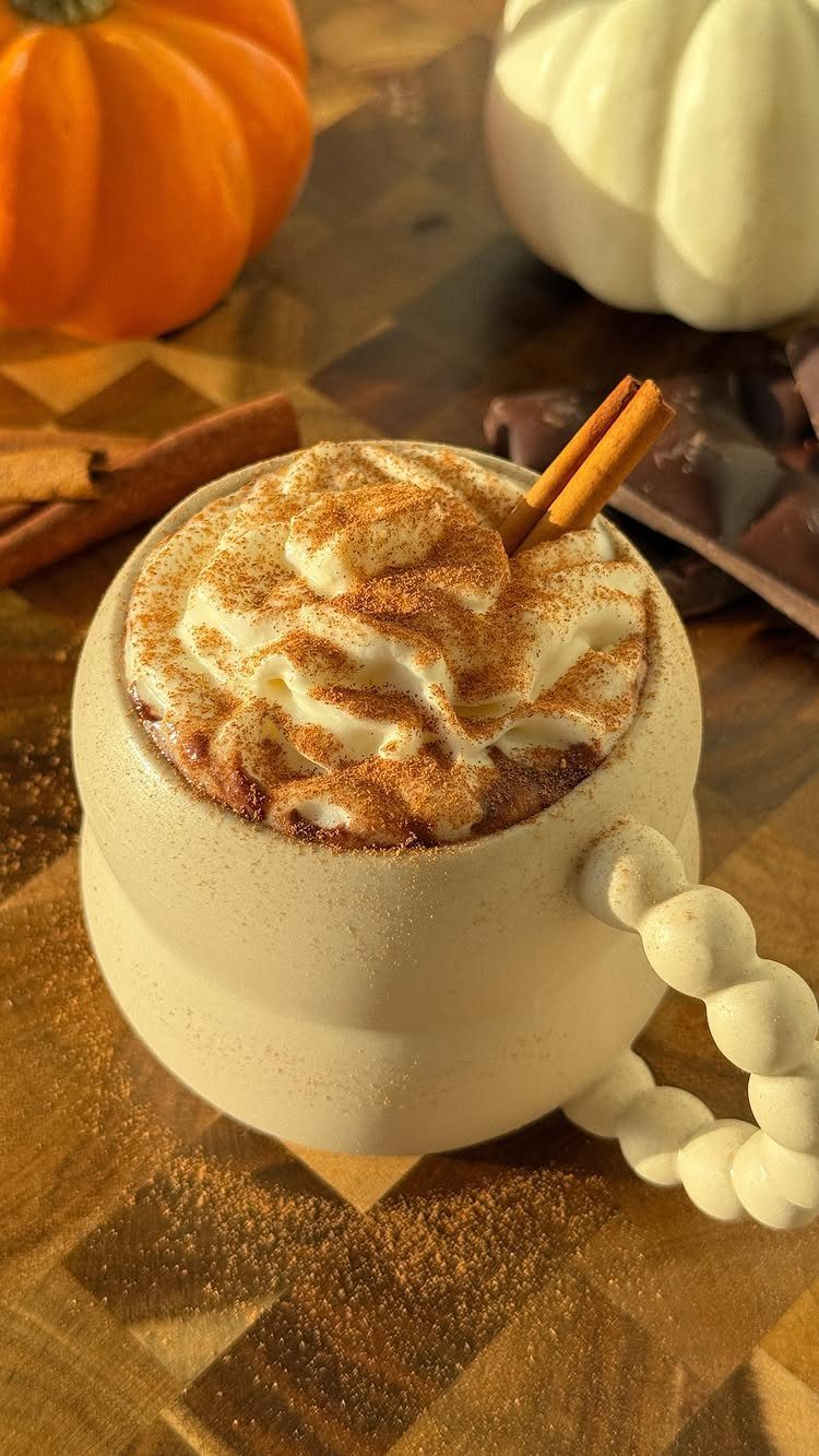 White hot chocolate with whipped cream and cinnamon in a ceramic mug.