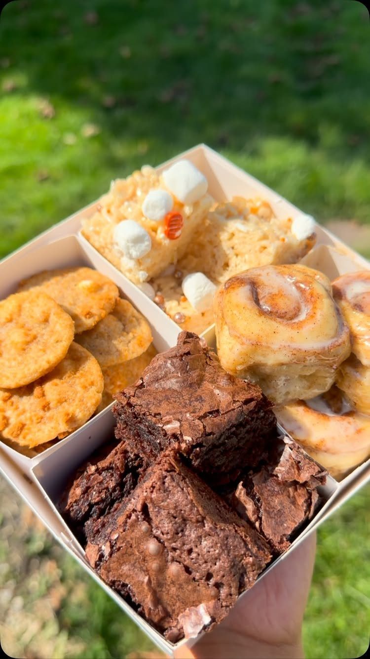 Assorted baked goods including brownies, cookies, and cinnamon rolls in a divided box.
