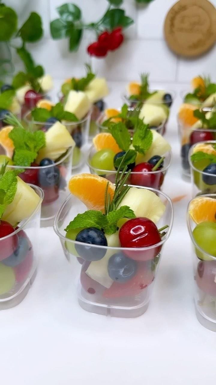 Fresh fruit cups with blueberries, cherries, and pineapple garnished with mint leaves.