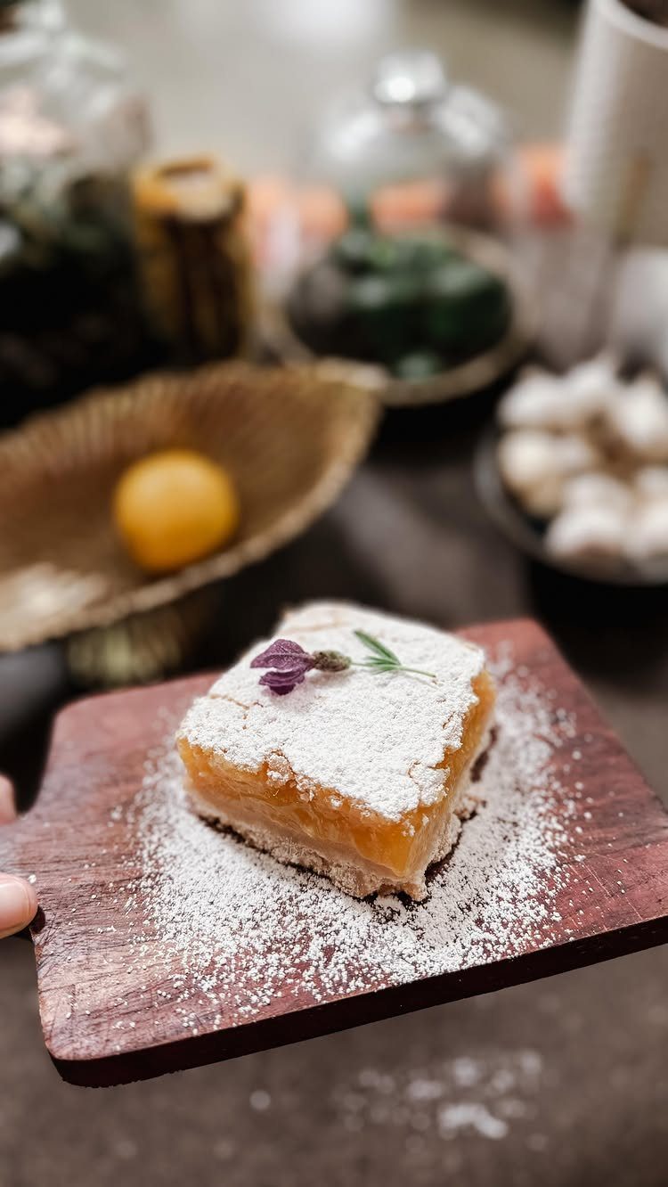 Lavender lemon bar with powdered sugar on a wooden board with a lemon background