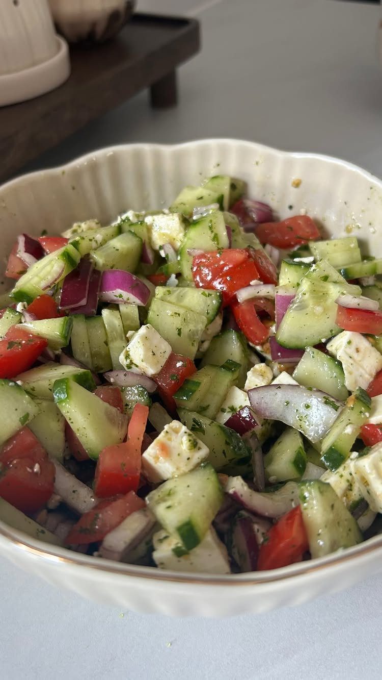 Tomato feta salad with cucumbers and red onion in a white bowl