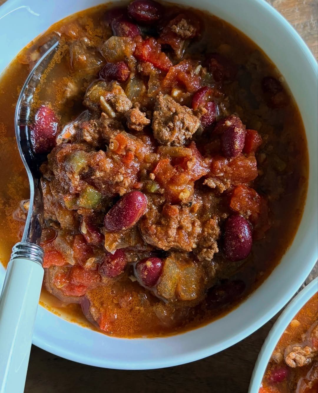 Hearty beef, bean and veggie chili in a light blue bowl with spoon.