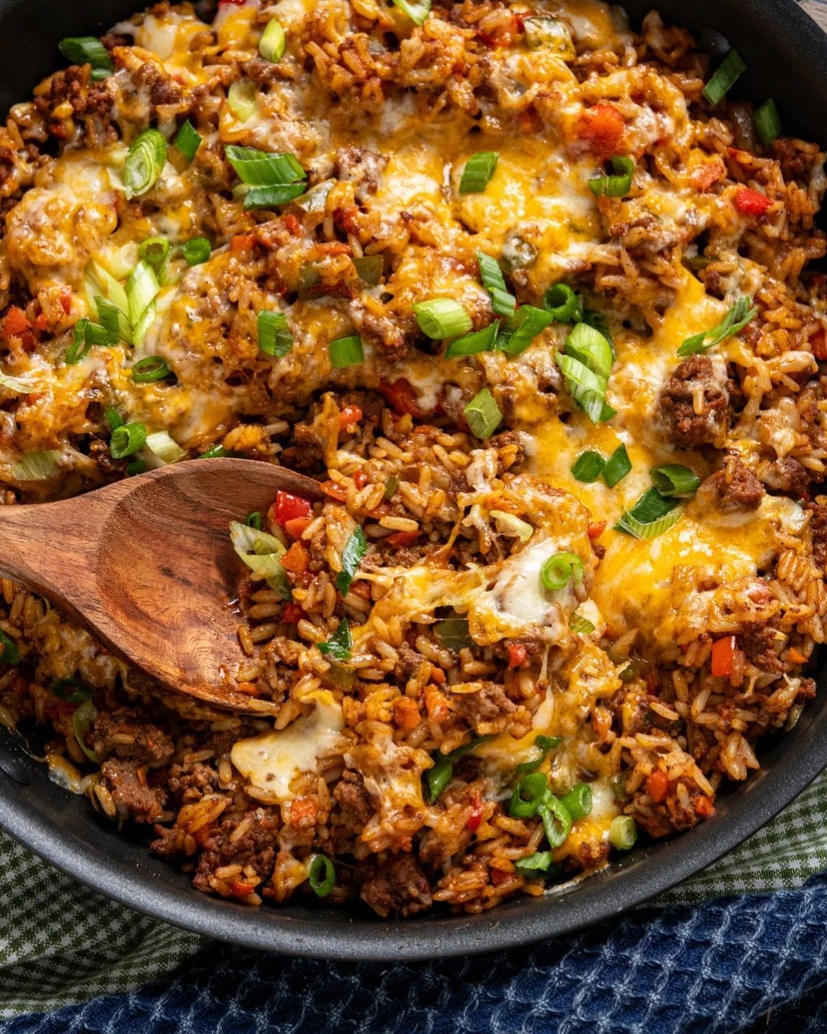 Beef and rice skillet with melted cheese and green onions in a pan