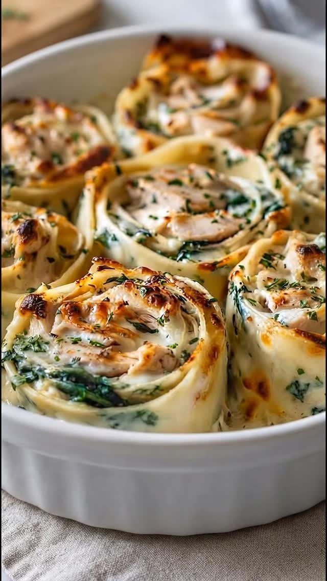 Lasagna rolls filled with spinach and ricotta cheese in a white baking dish