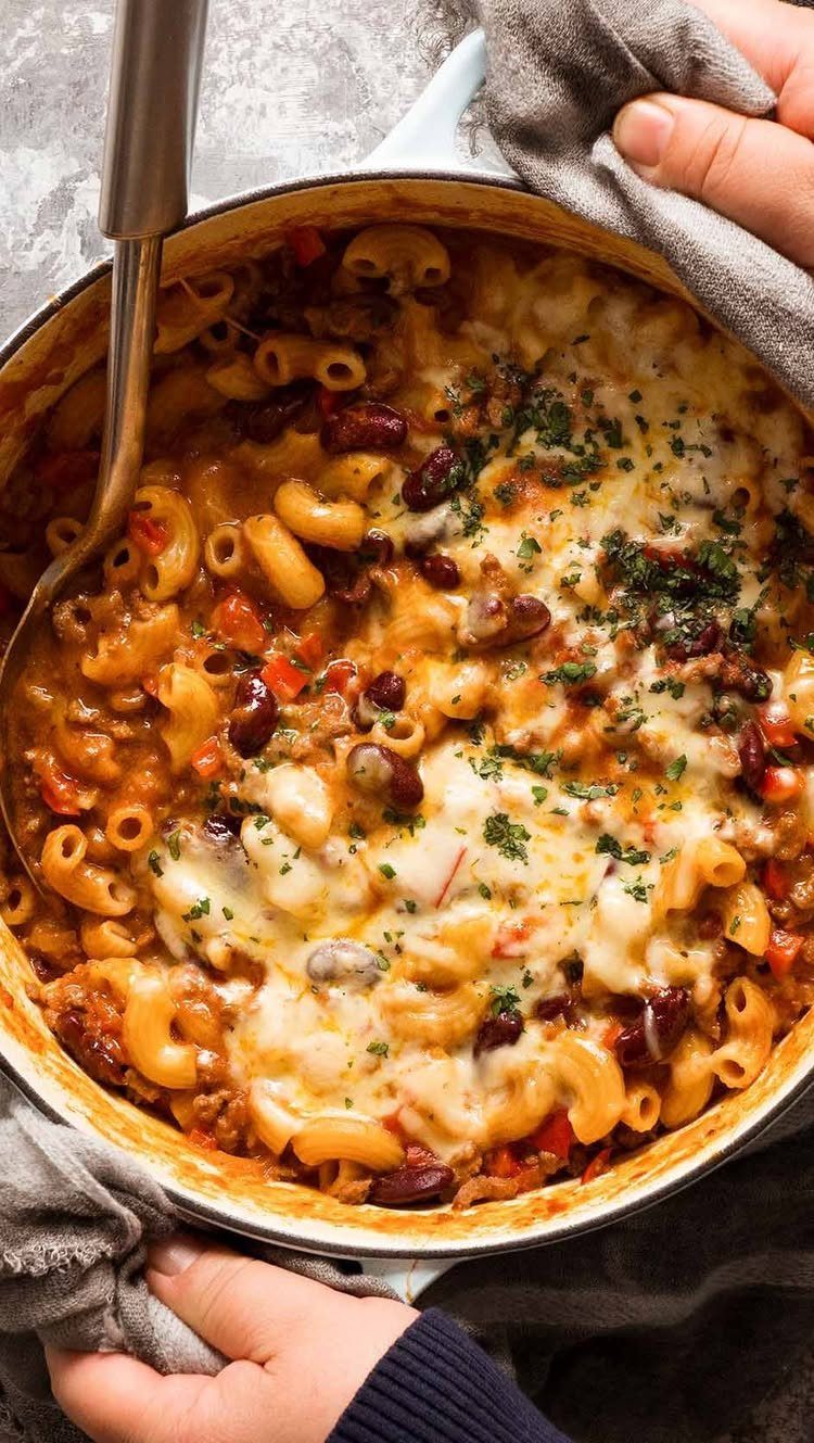 Macaroni and cheese with kidney beans and ground meat in a white skillet.