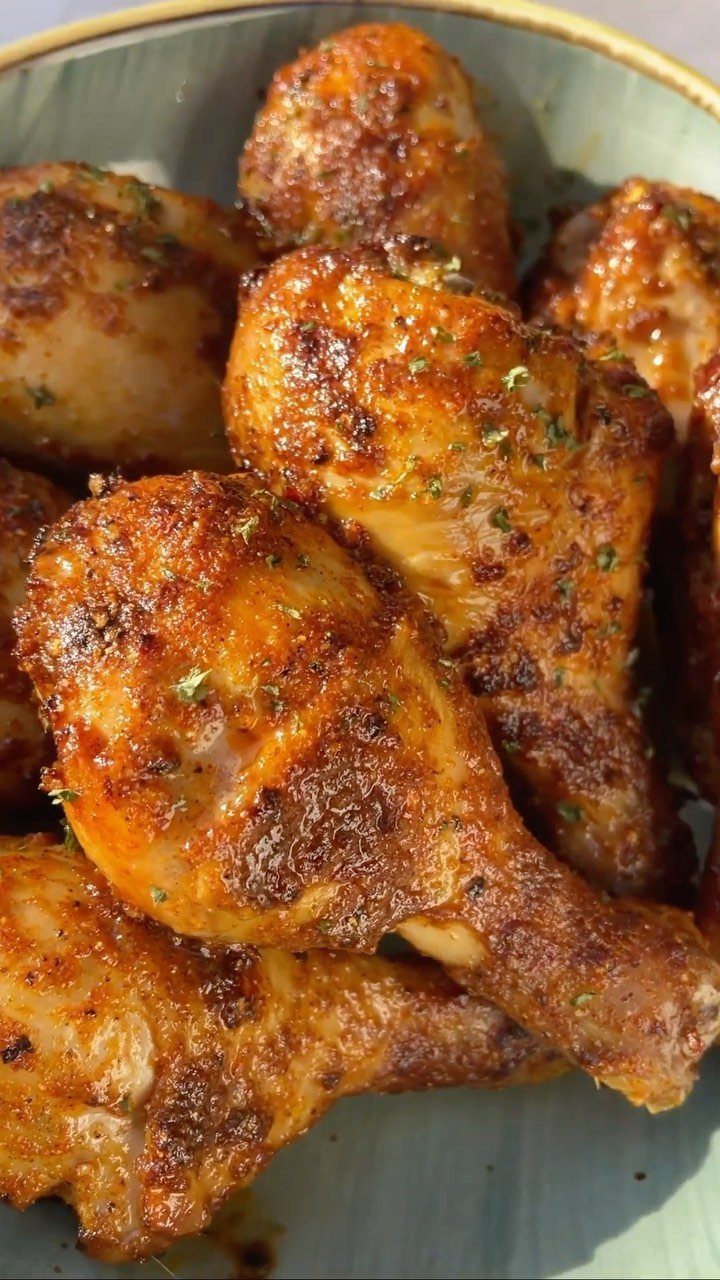Roasted chicken drumsticks with golden brown skin and herbs in a bowl