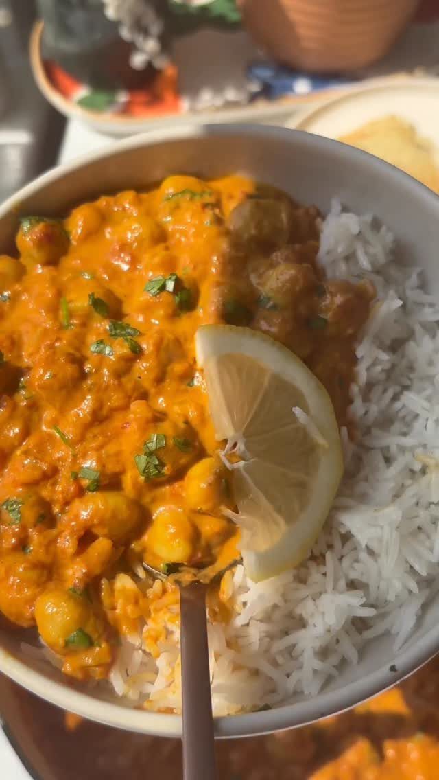 Chickpea curry with white rice, garnished with cilantro and a lemon wedge.