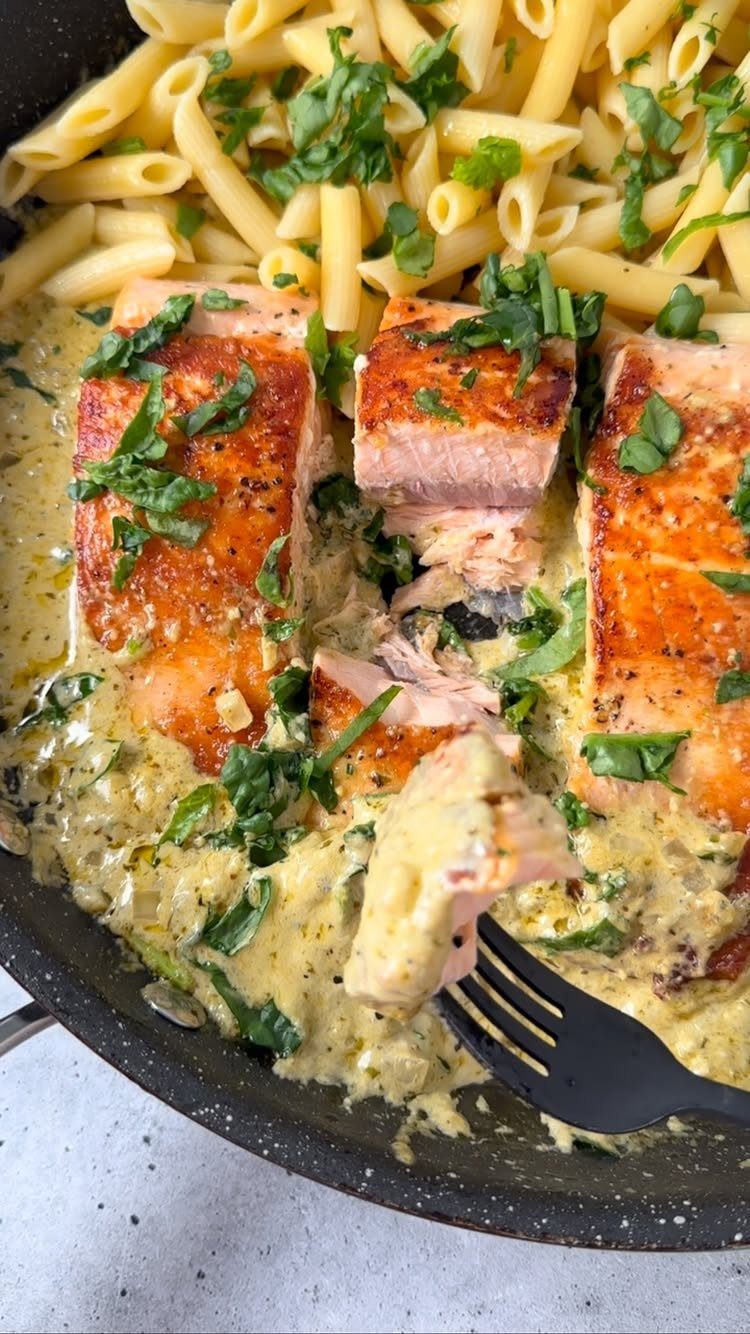 Salmon fillets in creamy pesto sauce served with penne pasta in a pan