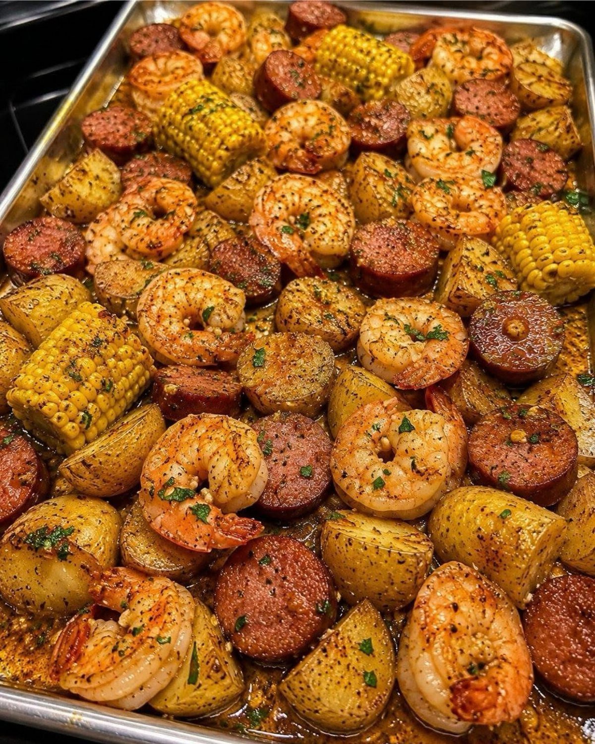 Cajun shrimp, sausage, corn, and potatoes seasoned and roasted on a sheet pan.