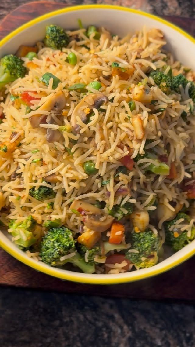 Vegetable fried rice with broccoli, mushrooms, and carrots in a yellow bowl