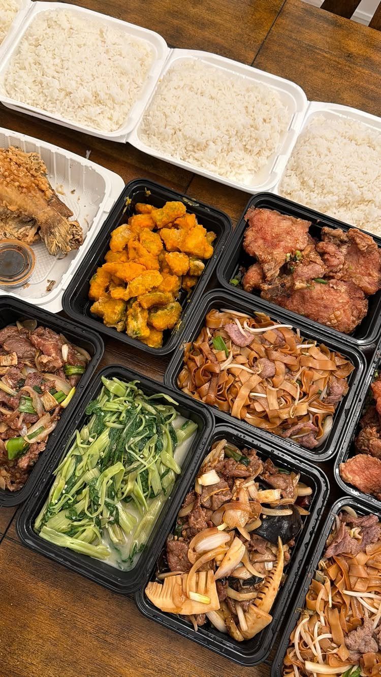 Various Asian takeout containers with rice and stir-fry dishes on a wooden table.