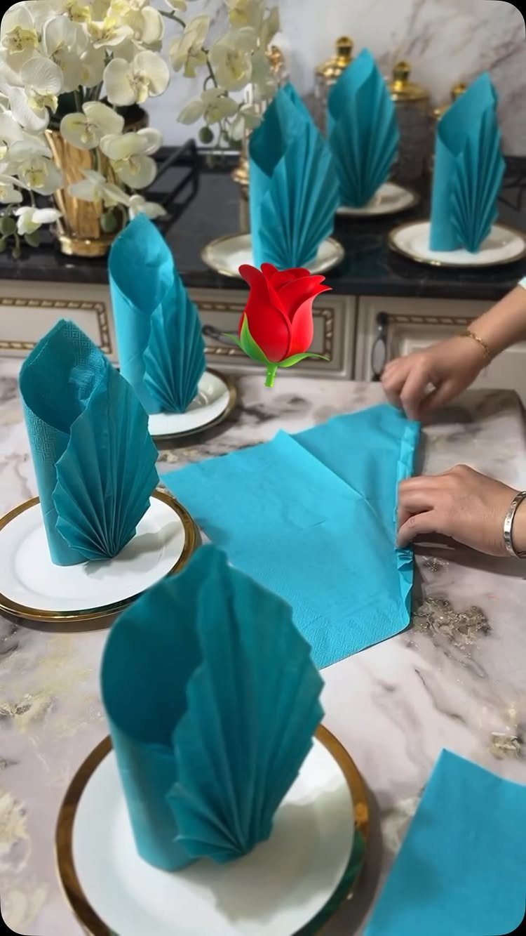 Blue napkins folded into fan shapes on white and gold plates.