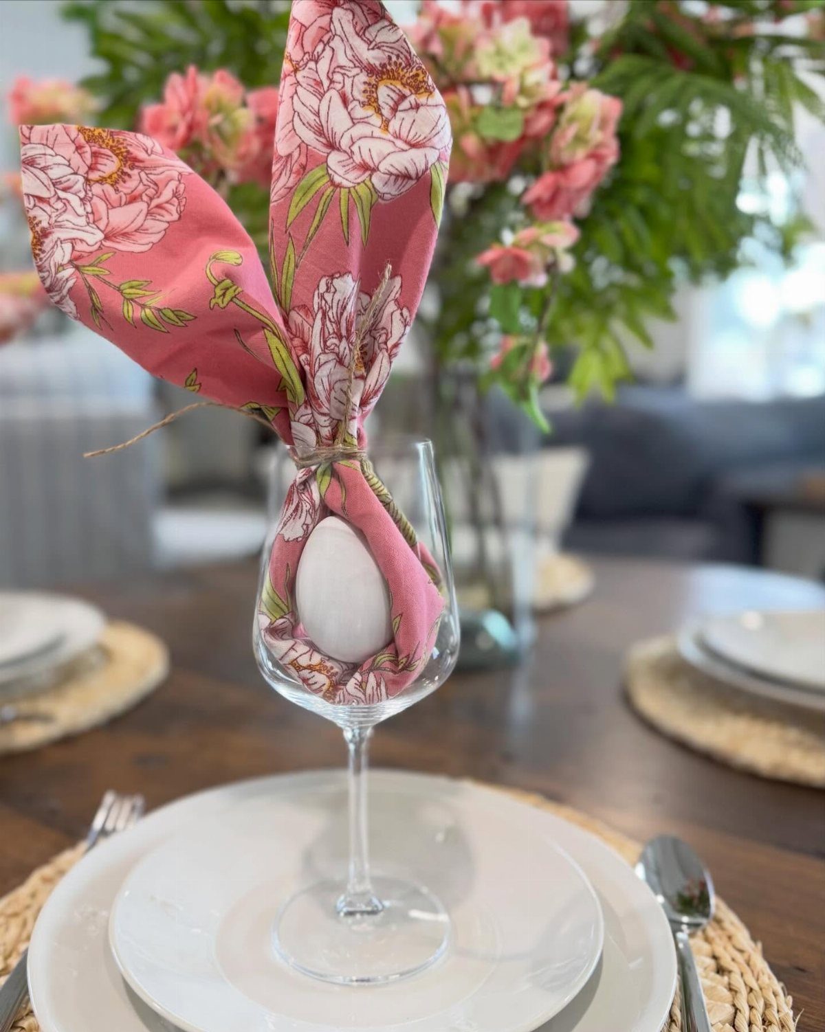 Pink floral napkin scrunched and tied around an egg in a wine glass.