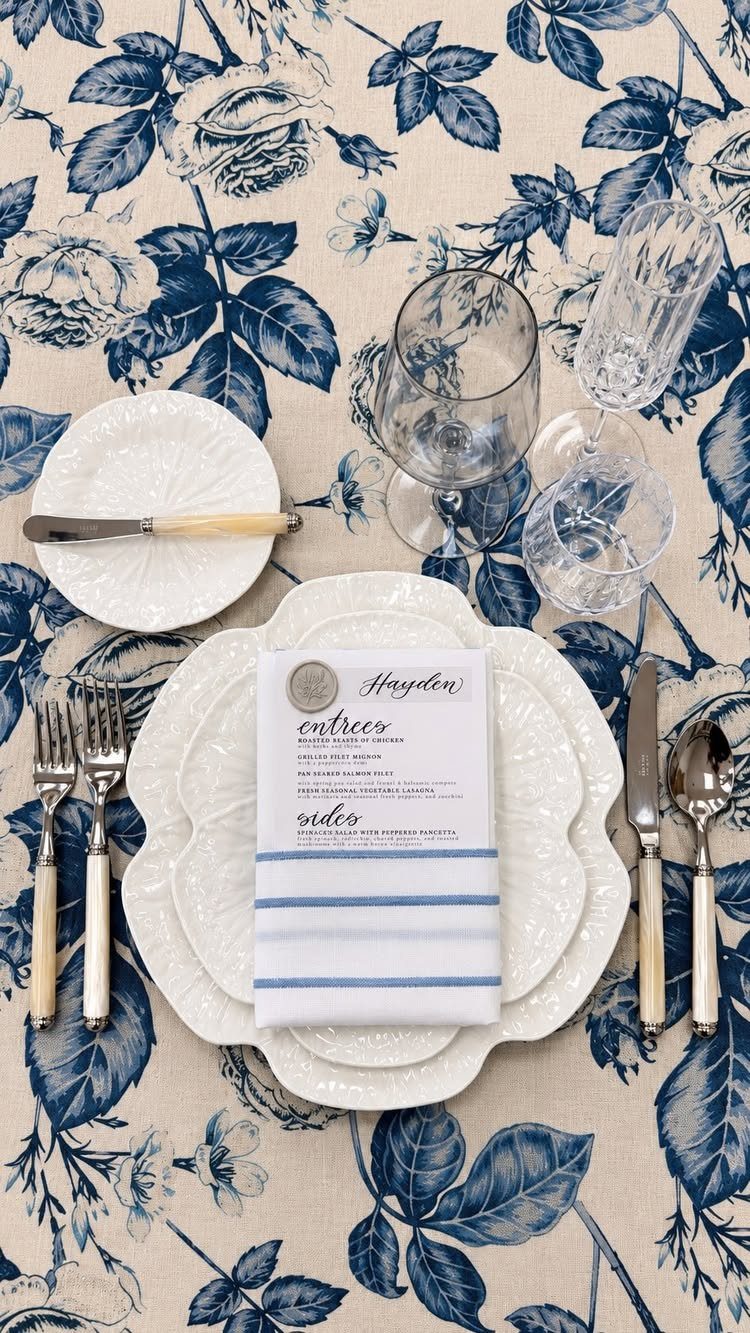 White striped napkin in a pocket fold holding a menu on a floral tablecloth.