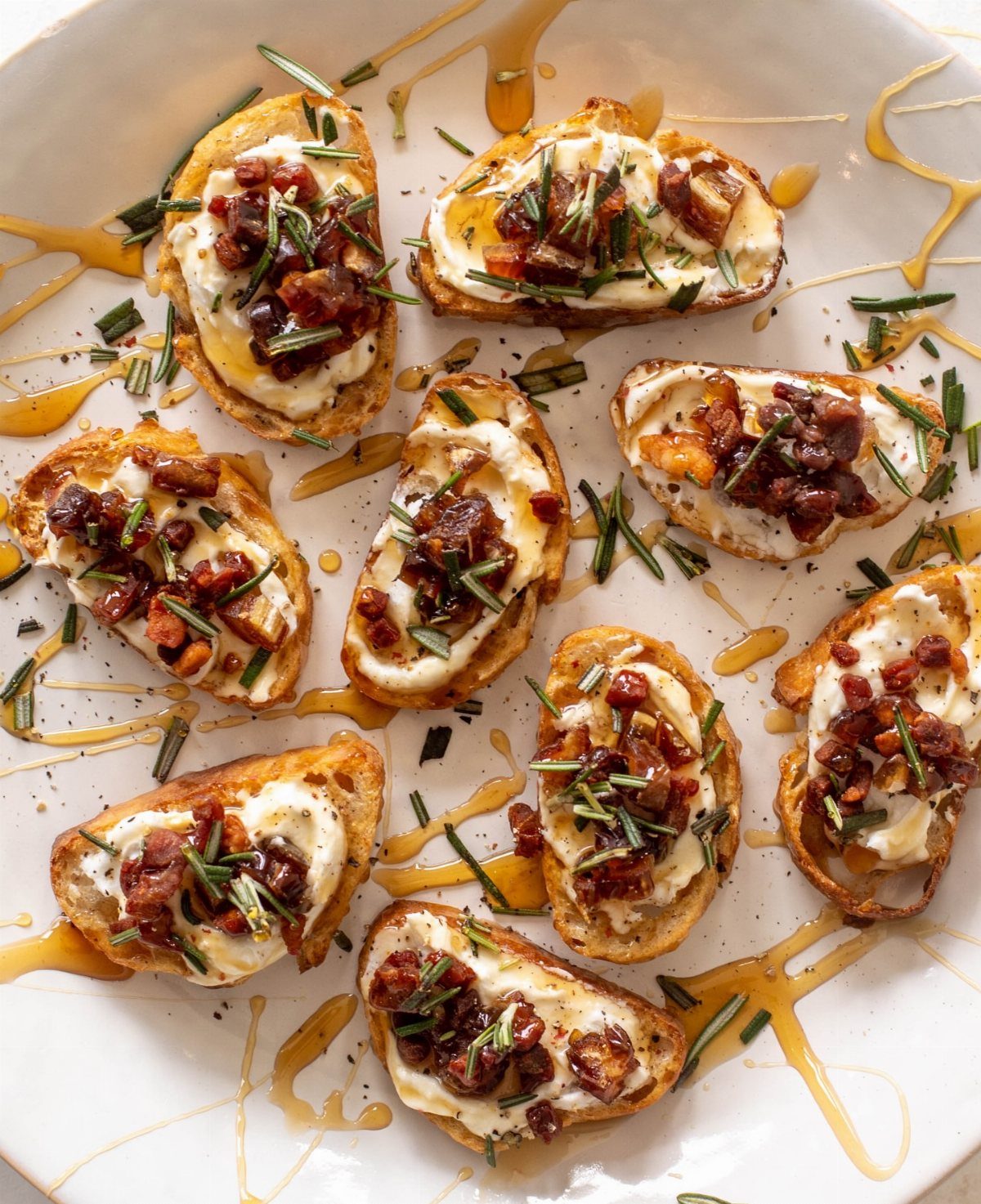 Toasted crostini topped with creamy cheese, bacon, and almonds drizzled with honey.